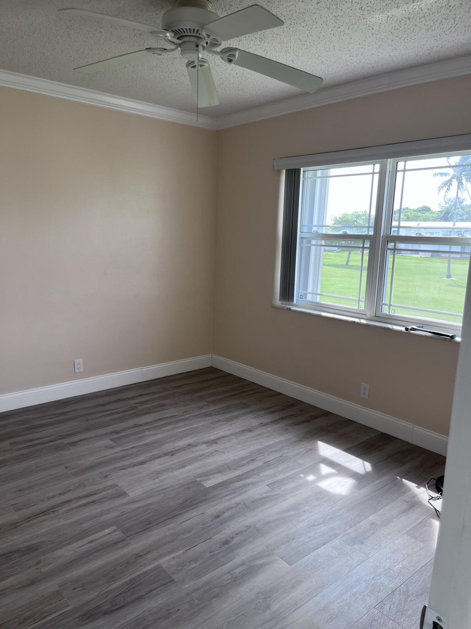 251 South Golf Boulevard, Unit 294 Pompano Beach, FL 33064 - Photo 16 of 36 a view of an empty room with wooden floor and a window