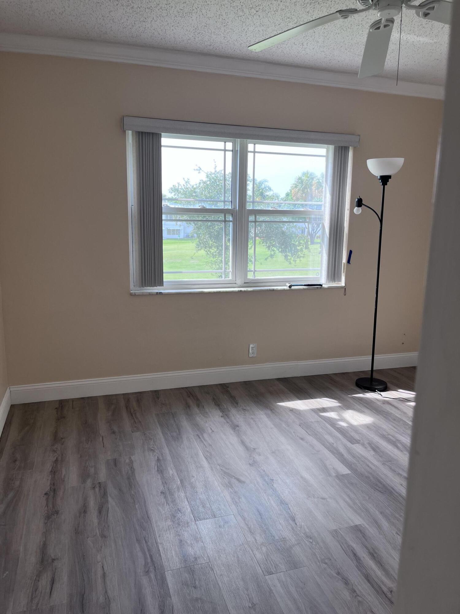 251 South Golf Boulevard, Unit 294 Pompano Beach, FL 33064 - Photo 17 of 36 a view of an empty room with wooden floor and a window