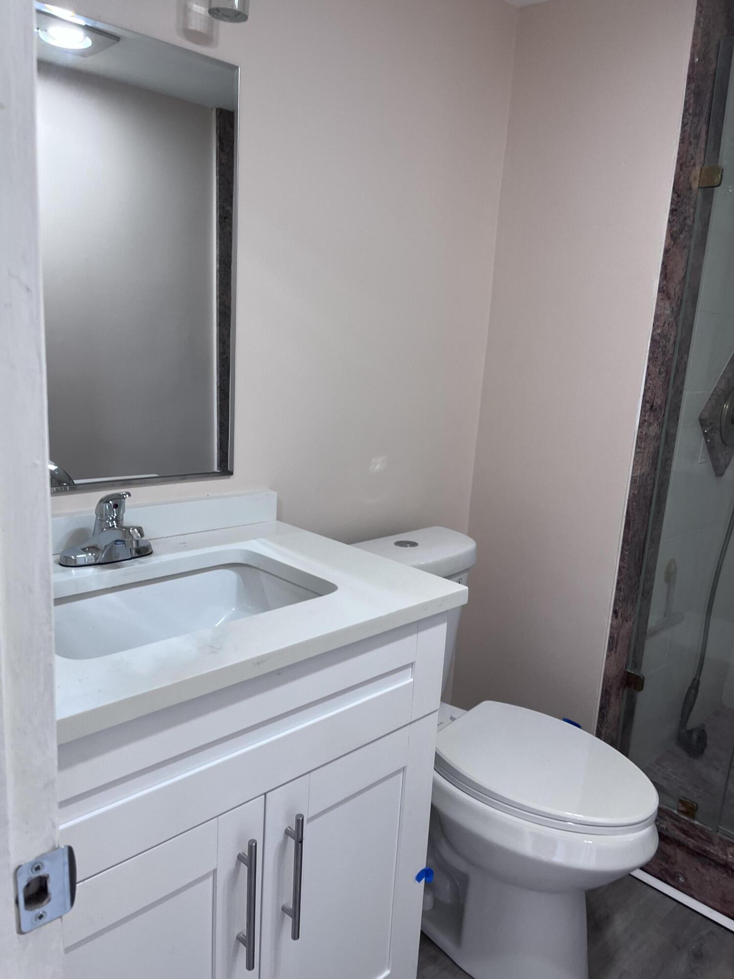 251 South Golf Boulevard, Unit 294 Pompano Beach, FL 33064 - Photo 31 of 36 a bathroom with a sink a toilet and a mirror