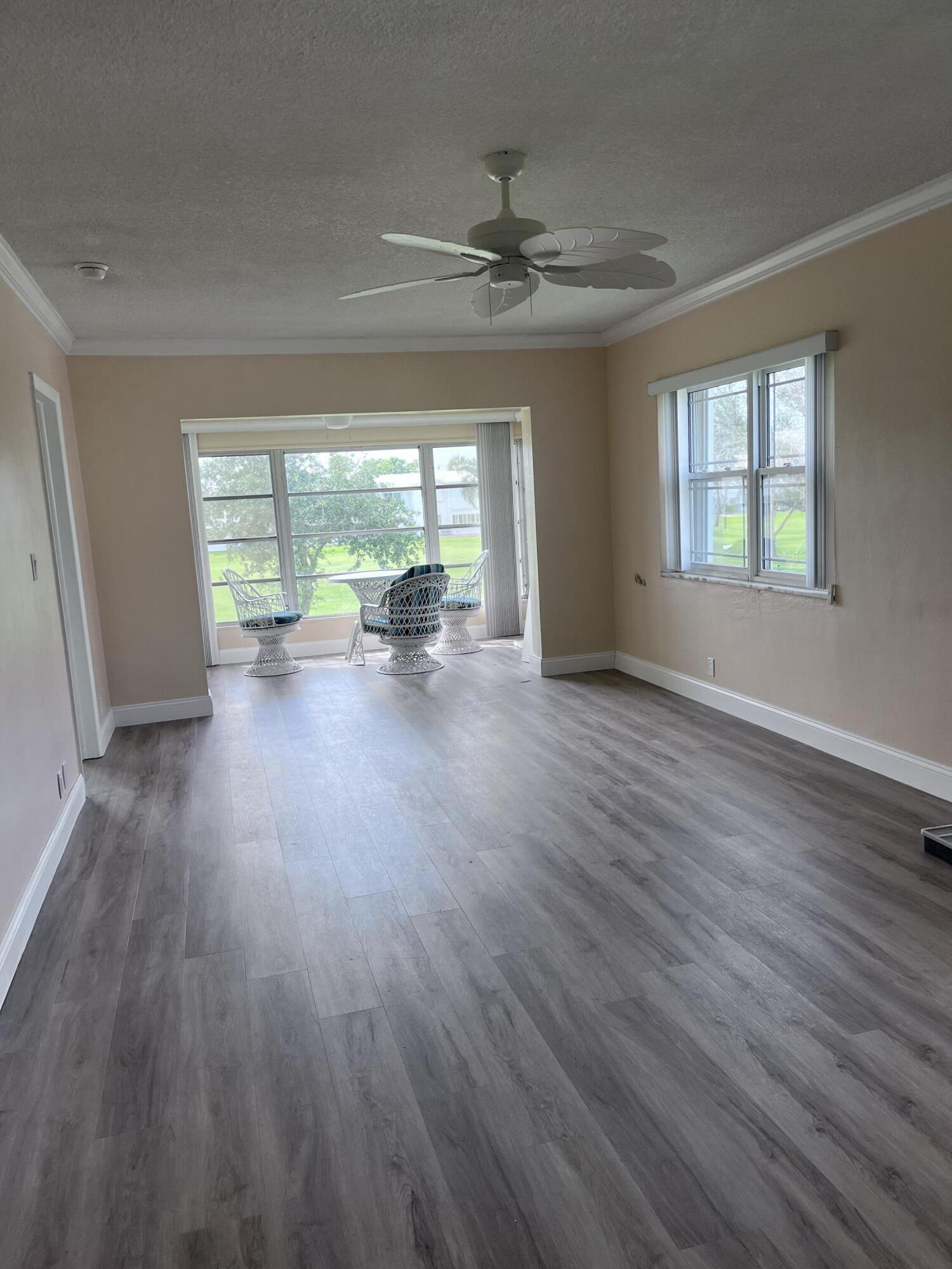 251 South Golf Boulevard, Unit 294 Pompano Beach, FL 33064 - Photo 4 of 36 a view of an empty room with wooden floor and a window