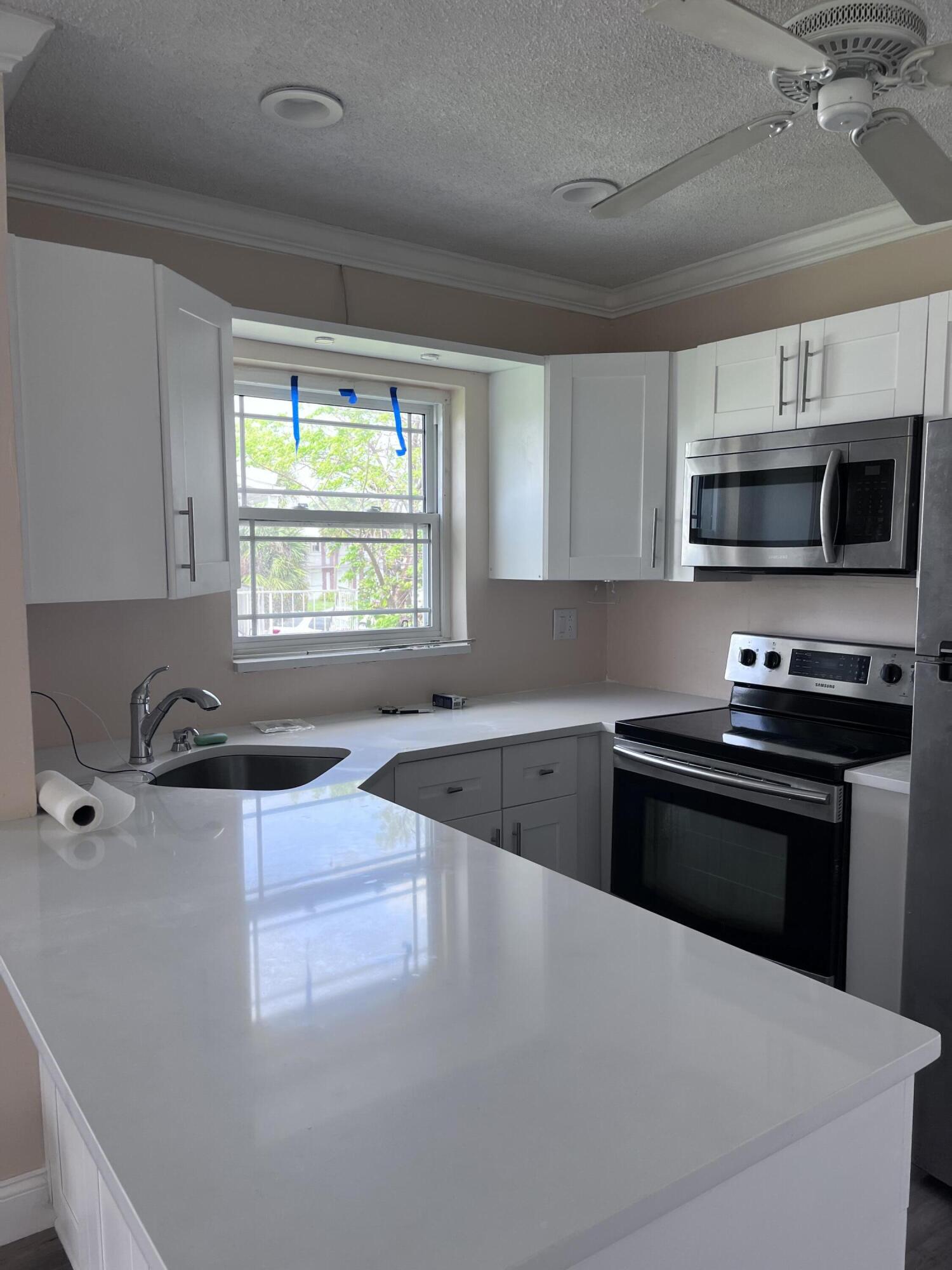 251 South Golf Boulevard, Unit 294 Pompano Beach, FL 33064 - Photo 5 of 36 a kitchen with stainless steel appliances a stove a microwave and a sink