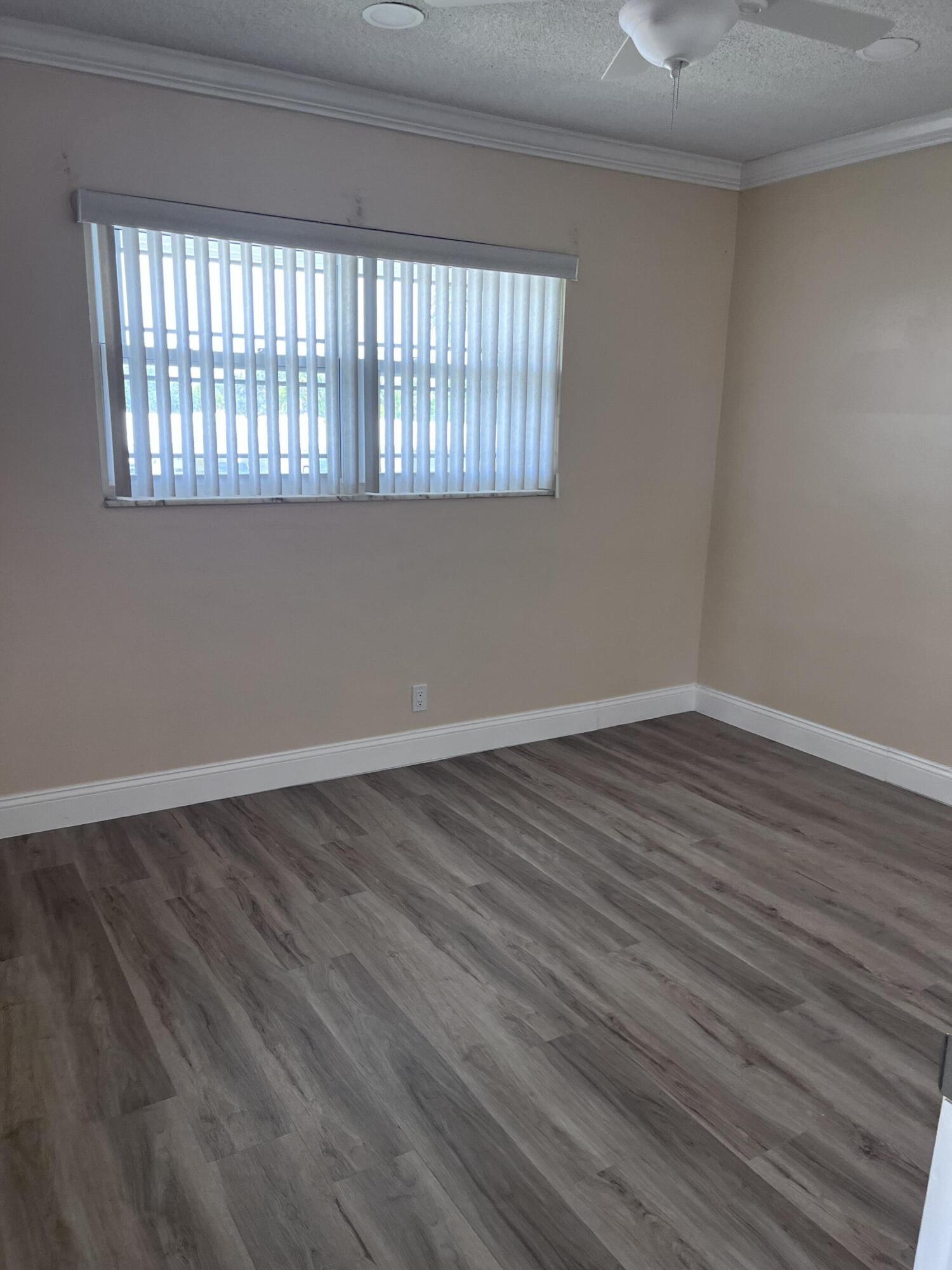 251 South Golf Boulevard, Unit 294 Pompano Beach, FL 33064 - Photo 8 of 36 a view of an empty room with wooden floor and a window