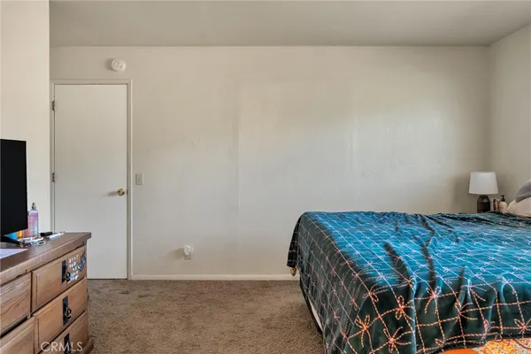 a bedroom with a bed and a flat tv screen on dresser