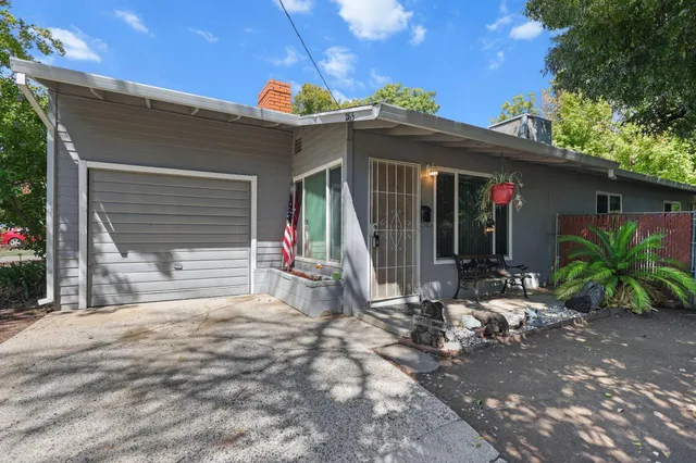 a view of a house with a small yard and floor to ceiling window and potted plants
