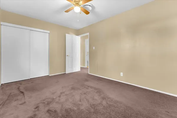 a view of an empty room and chandelier fan