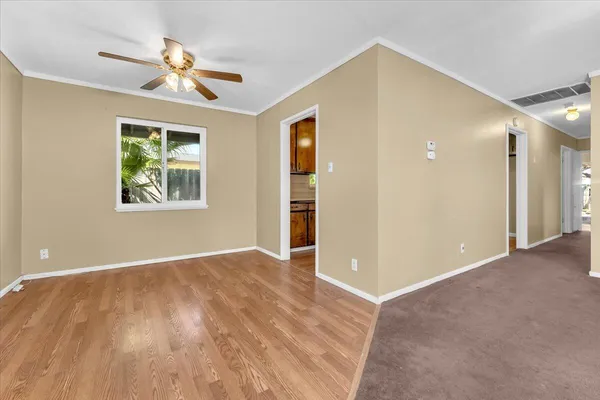a view of an empty room with window and wooden floor