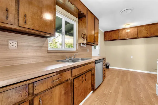 a kitchen with stainless steel appliances granite countertop a sink a stove and a wooden floors