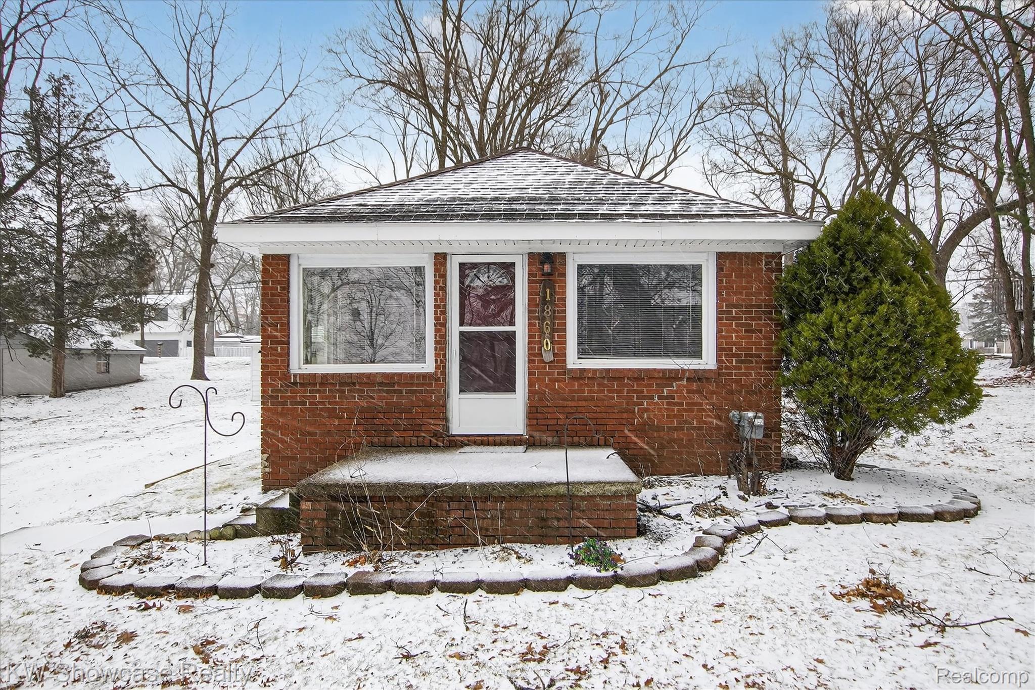 View of front of house with a shingled roof and brick siding