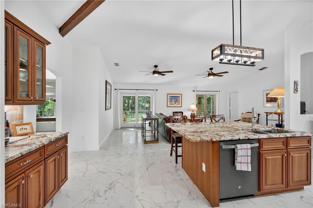 1741 17th Street Southwest Naples, FL 34117 - Photo 50 of 50 Kitchen featuring brown cabinets, light stone countertops, decorative light fixtures, and open floor plan