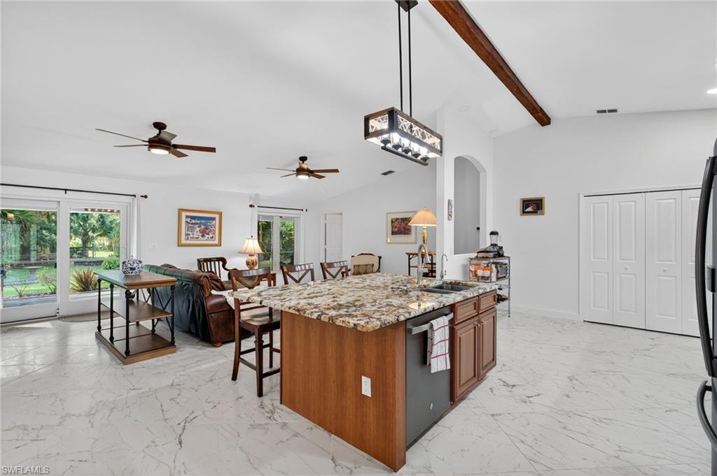 1741 17th Street Southwest Naples, FL 34117 - Photo 13 of 50 Kitchen with a kitchen breakfast bar, a kitchen island with sink, light stone countertops, pendant lighting, and arched walkways