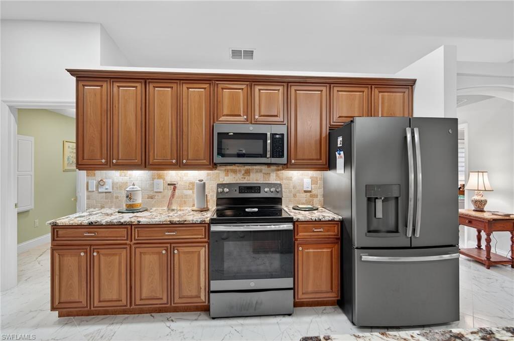 1741 17th Street Southwest Naples, FL 34117 - Photo 16 of 50 Kitchen with light marble finish flooring, appliances with stainless steel finishes, light stone countertops, and brown cabinets