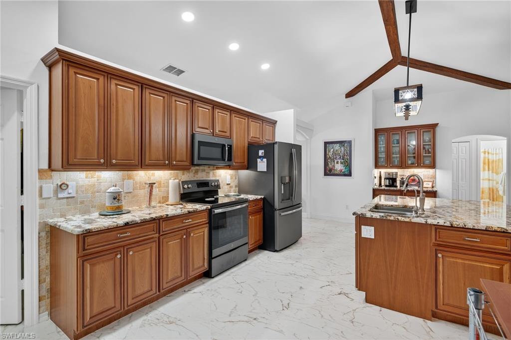 1741 17th Street Southwest Naples, FL 34117 - Photo 17 of 50 Kitchen featuring backsplash, stainless steel appliances, brown cabinetry, pendant lighting, and recessed lighting