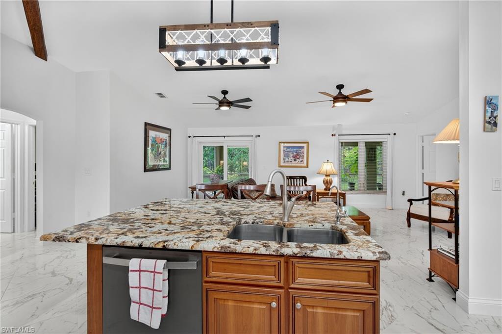 1741 17th Street Southwest Naples, FL 34117 - Photo 18 of 50 Kitchen with brown cabinets, hanging light fixtures, light satin finish porcelain tile flooring, stainless steel dishwasher, and light stone countertops