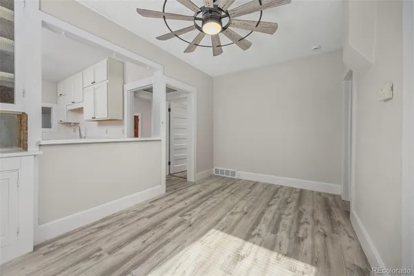 a view of kitchen and empty room with wooden floor