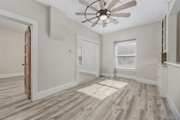 a view of empty room with wooden floor and fan