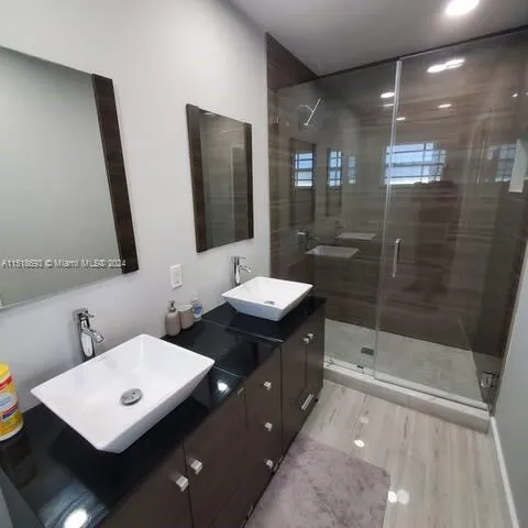a bathroom with a sink a toilet a mirror and shower