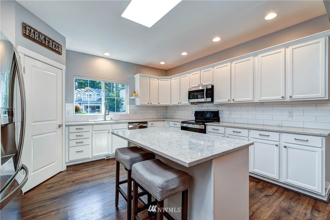 214 159th Street Southeast Bothell, WA 98012 - Photo 4 of 26 a kitchen with a stove a sink a microwave a refrigerator and white cabinets