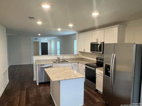 a kitchen with kitchen island granite countertop stainless steel appliances cabinets a sink and a counter top space