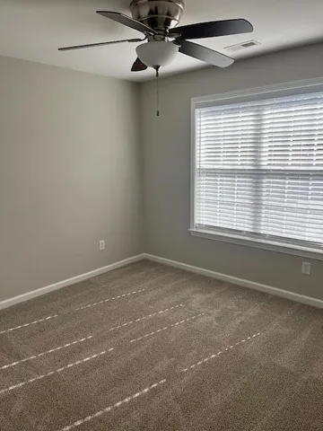 an empty room with windows and fan