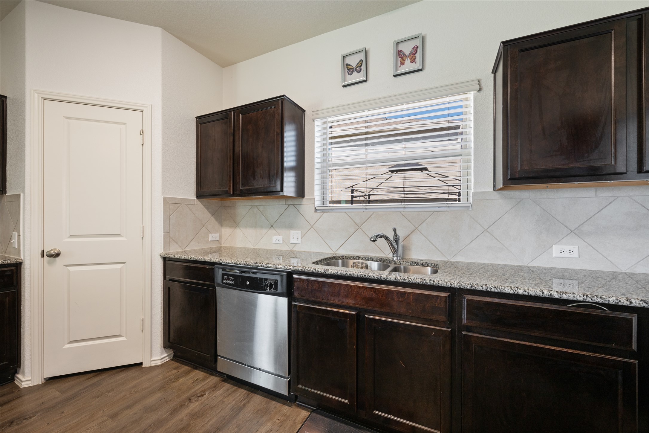 524 Circle Way, Unit 12F Jarrell, TX 76537 - Photo 13 of 34 Kitchen with dark wood finish cabinetry, stainless steel dishwasher, light stone counters, dark wood finished floors, and backsplash