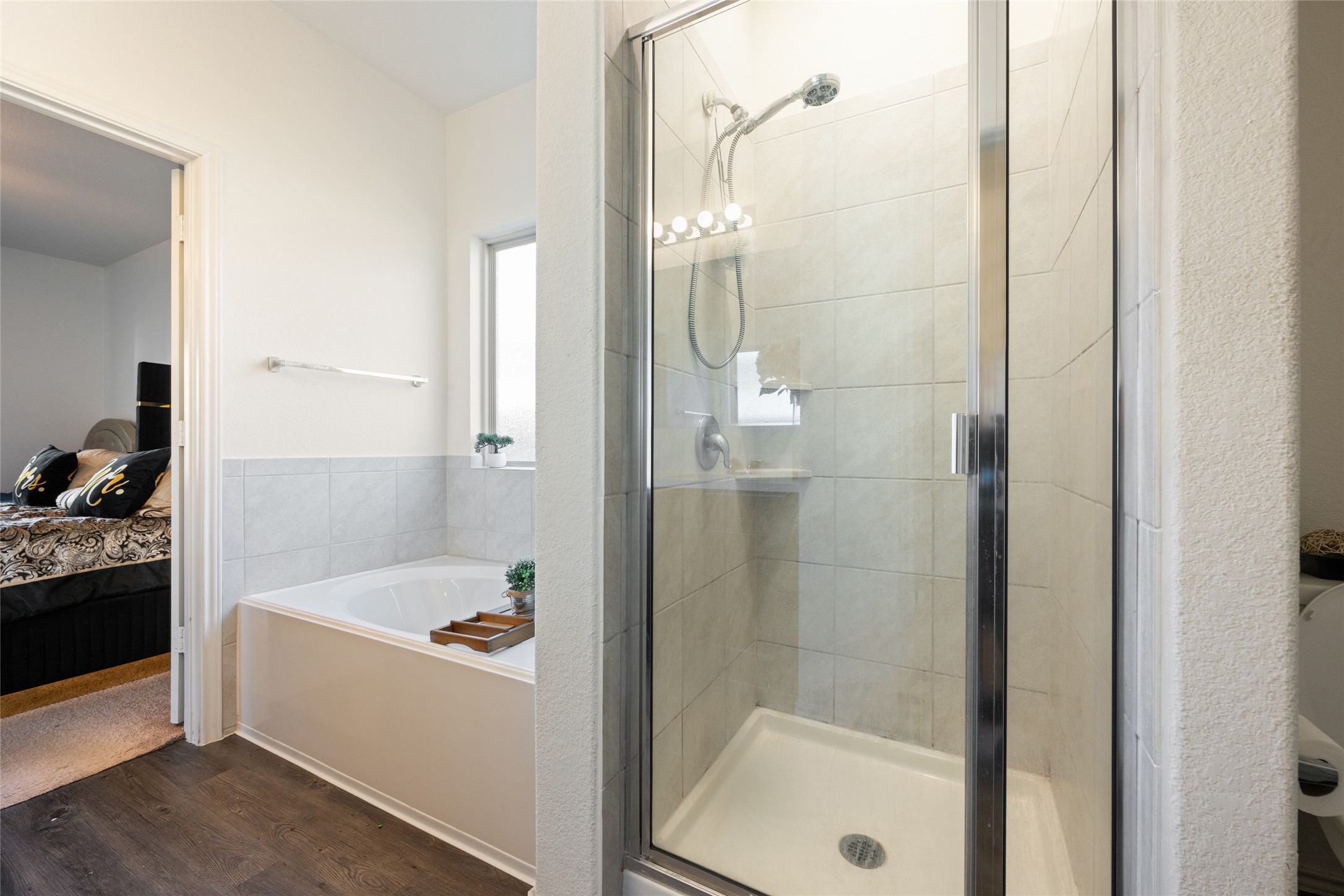 524 Circle Way, Unit 12F Jarrell, TX 76537 - Photo 18 of 34 Bathroom featuring a bath, ensuite bath, a stall shower, and dark wood finished floors