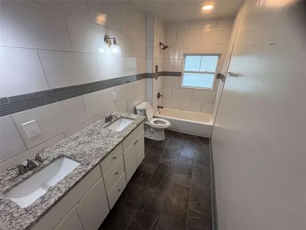 a bathroom with a granite countertop sink a toilet and bathtub