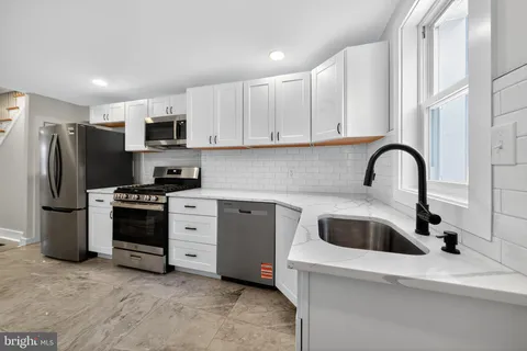 a kitchen with stainless steel appliances a refrigerator sink and white cabinets