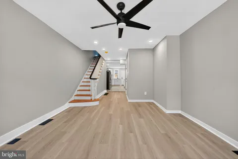 a view of an empty room with wooden floor a ceiling fan