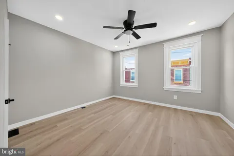 a view of a big room with wooden floor a ceiling fan and windows