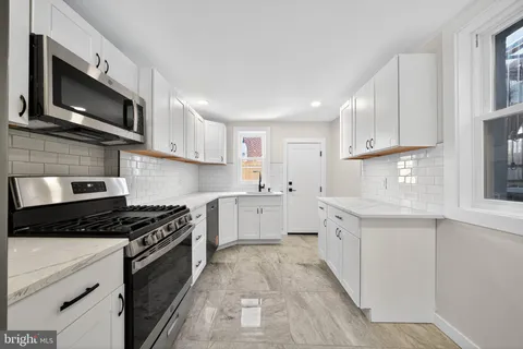 a kitchen with stainless steel appliances granite countertop a stove top oven a sink dishwasher and a refrigerator with wooden cabinets