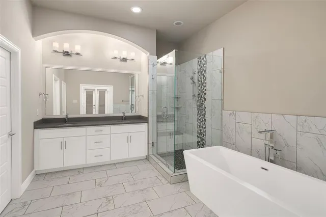 a bathroom with a bathtub a sink a mirror and a shower