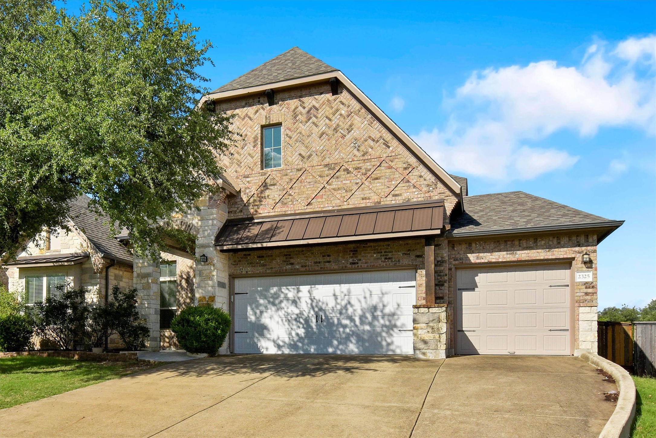 2325 Blended Tree Ranch Drive Leander, TX 78641 - Photo 3 of 35 A striking exterior combines rich brickwork and stone accents, creating a grand facade with dual garage doors.