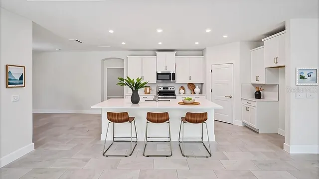 a dining room with kitchen island stainless steel appliances kitchen island granite countertop a table and chairs in it