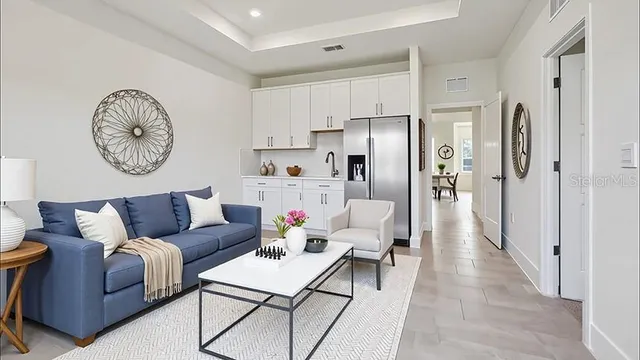 a living room with furniture a clock and a view of kitchen