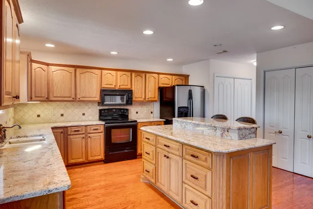 a kitchen with stainless steel appliances granite countertop a kitchen island hardwood floor sink stove and granite counter top