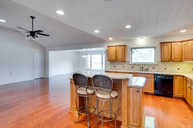 a kitchen with granite countertop a stove a sink a dining table and chairs
