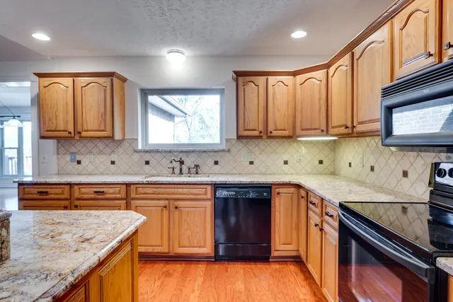 a kitchen with stainless steel appliances granite countertop wooden cabinets and a stove top oven