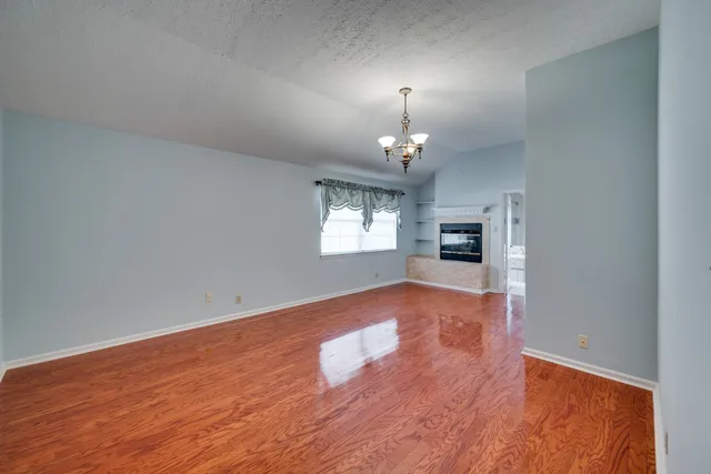 an empty room with fireplace and wooden floor