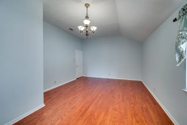 an empty room with wooden floor and chandelier