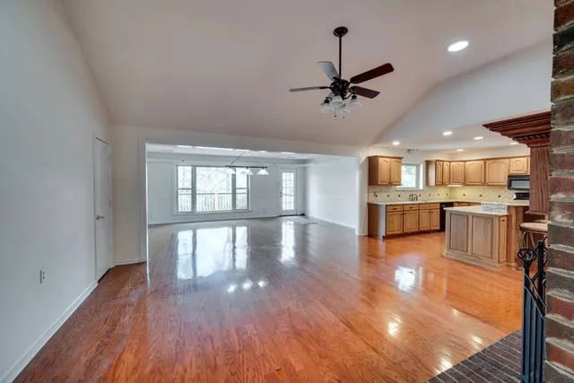 a view of a kitchen and an empty room with wooden floor