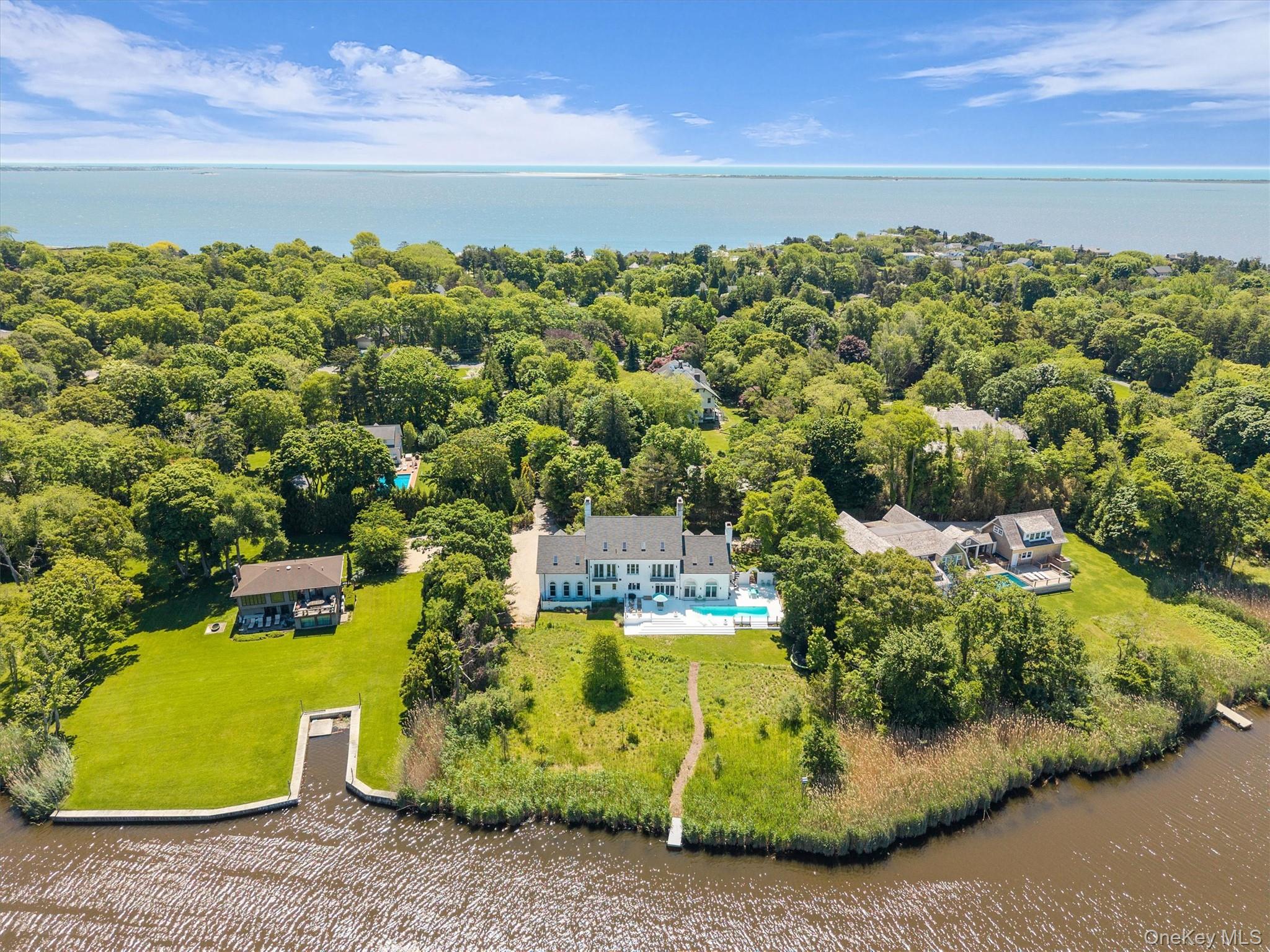 68 South Howells Point Road Bellport, NY 11713 - Photo 2 of 47 Waterfront property featuring a white multi-story residence with a pool, expansive lawn, and a private dock
