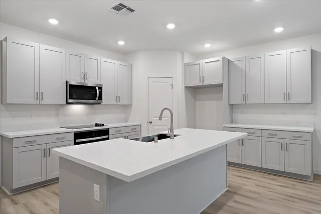 a kitchen with kitchen island a sink stainless steel appliances and white cabinets