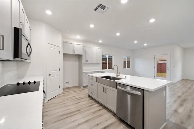 a open kitchen with stainless steel appliances granite countertop a sink and dishwasher a stove top oven with wooden floor