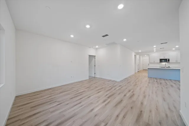 a view of a kitchen with kitchen island a sink wooden floor and a large window