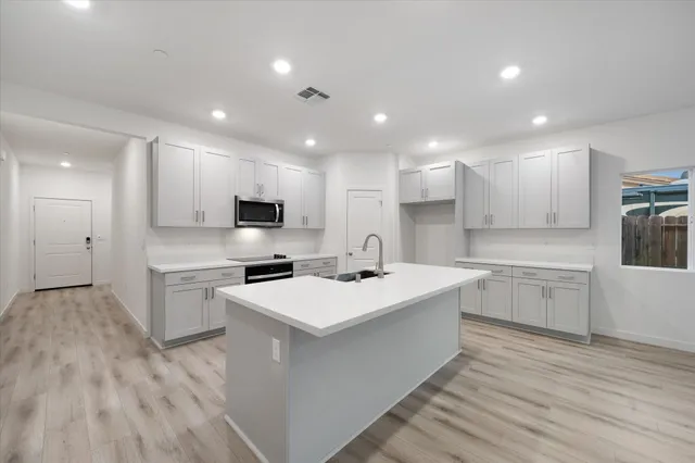 a kitchen with white cabinets appliances and sink