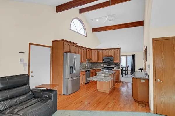 a living room with stainless steel appliances kitchen island granite countertop furniture and a wooden floor