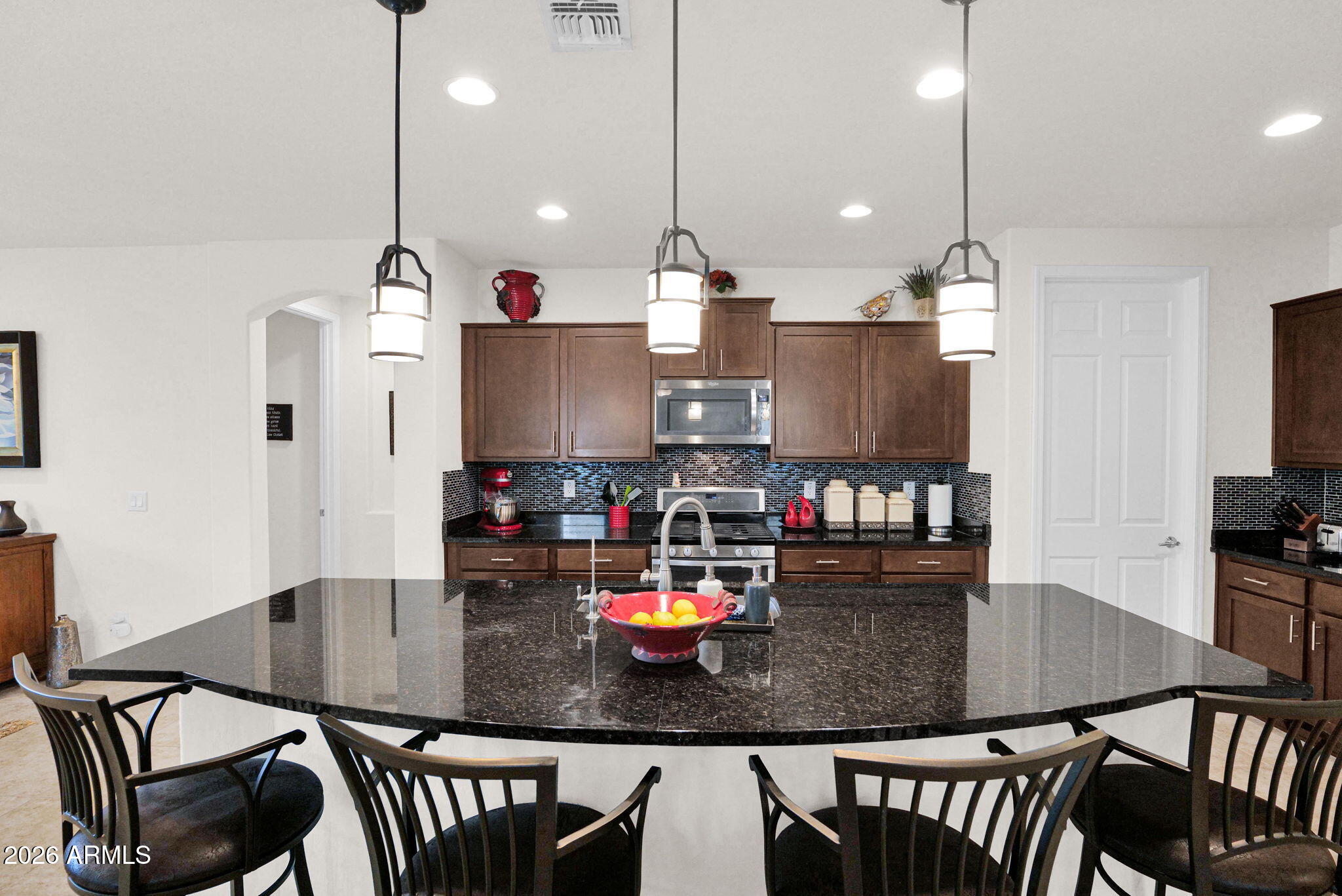 7438 West Noble Prairie Way Florence, AZ 85132 - Photo 22 of 38 a kitchen with stainless steel appliances granite countertop a dining table chairs and stove top oven