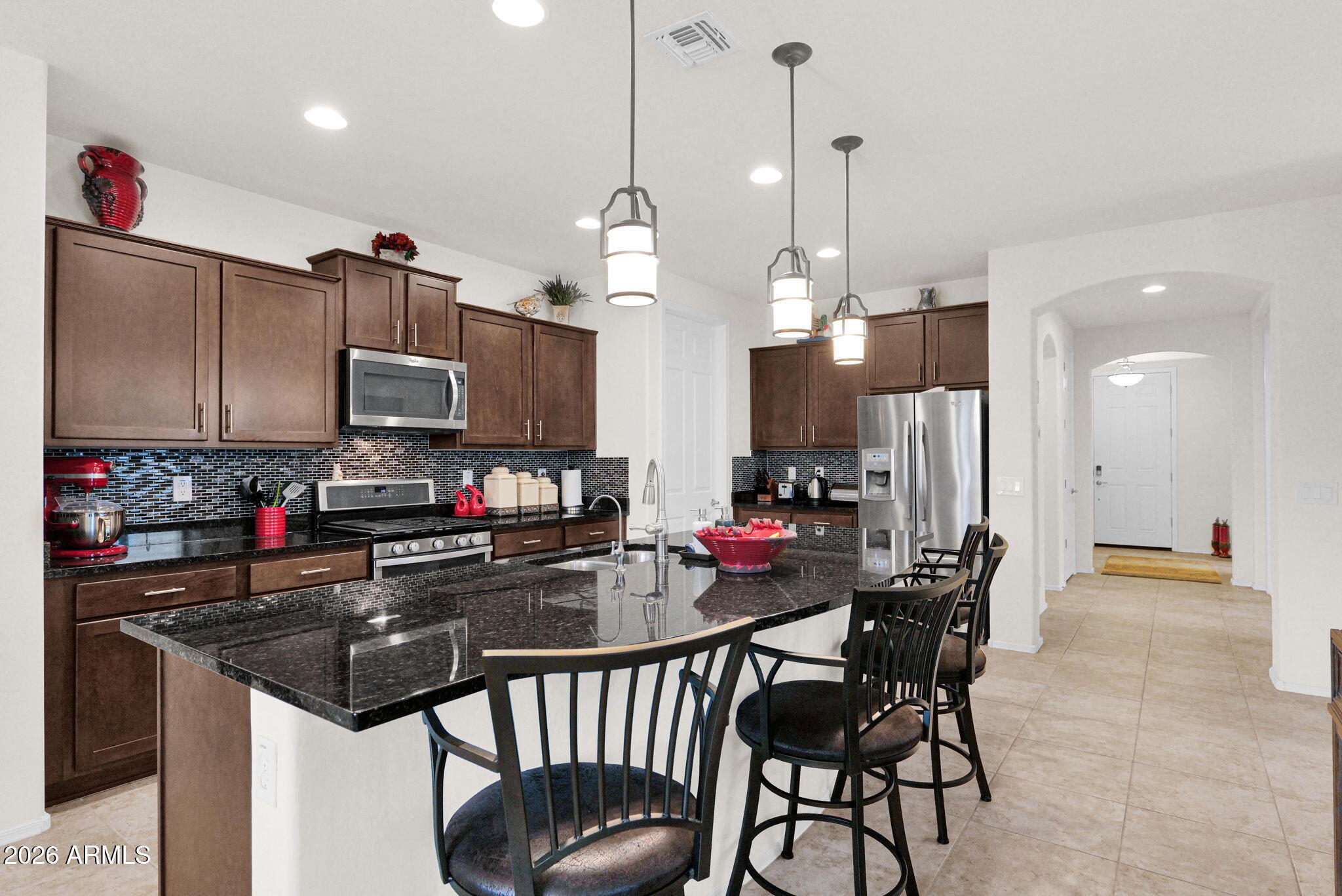7438 West Noble Prairie Way Florence, AZ 85132 - Photo 23 of 38 a kitchen with stainless steel appliances kitchen island granite countertop a sink a stove and a refrigerator