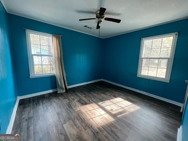 a view of empty room with wooden floor and fan