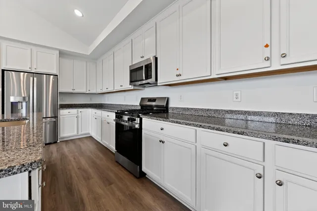a kitchen with granite countertop white cabinets white stainless steel appliances and granite counter tops